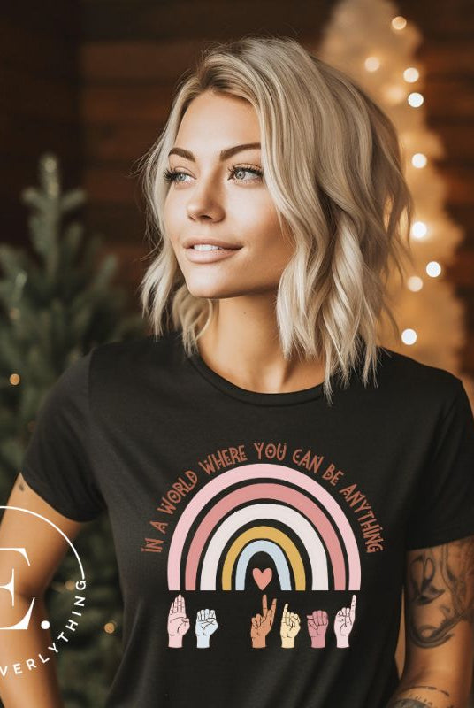 American sign language shirt with a rainbow and the phrase "In a world where you can be anything" and hands signing 'Be Kind' at the bottom on the rainbow on a black colored shirt.