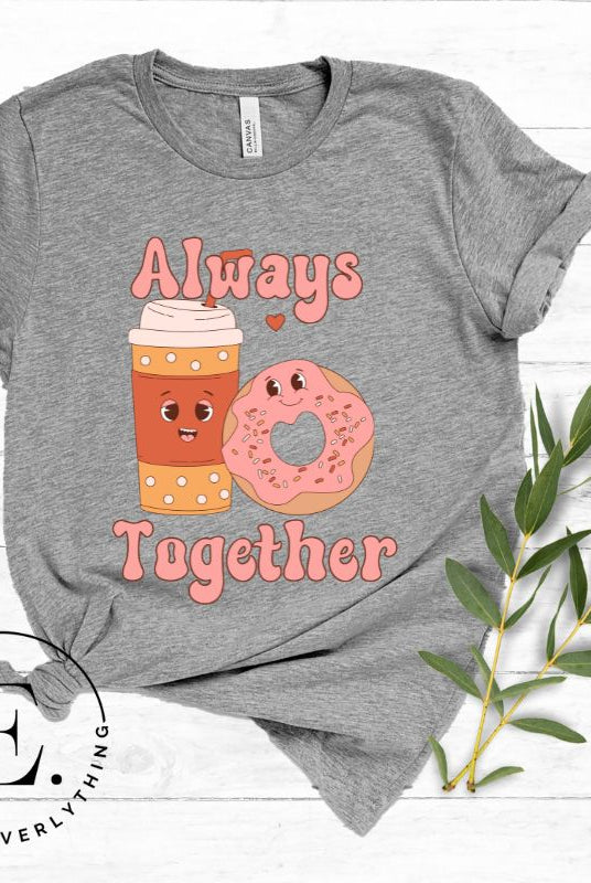 Celebrate love with our adorable Valentine's Day graphic tee! Featuring a smiling coffee cup and a cheerful donut holding hands, on a grey shirt. 