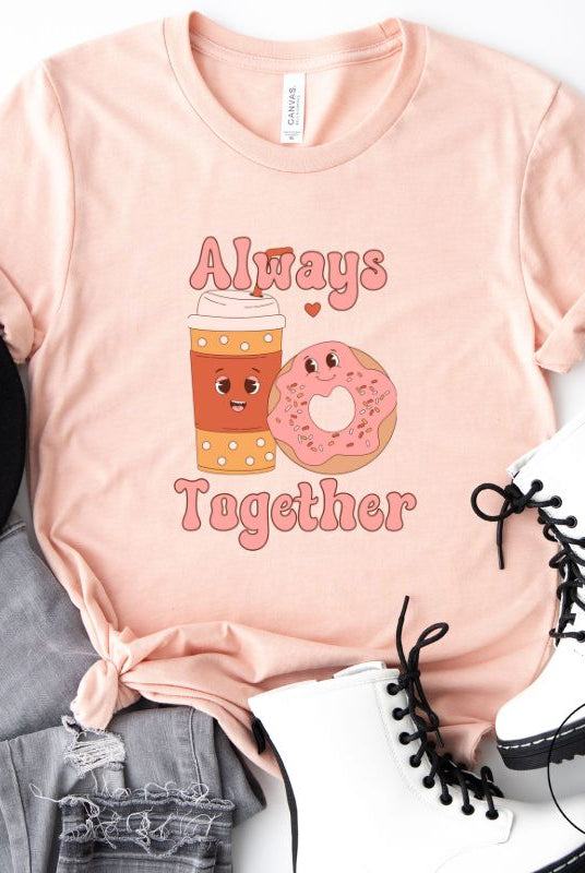 Celebrate love with our adorable Valentine's Day graphic tee! Featuring a smiling coffee cup and a cheerful donut holding hands, on a peach shirt. 