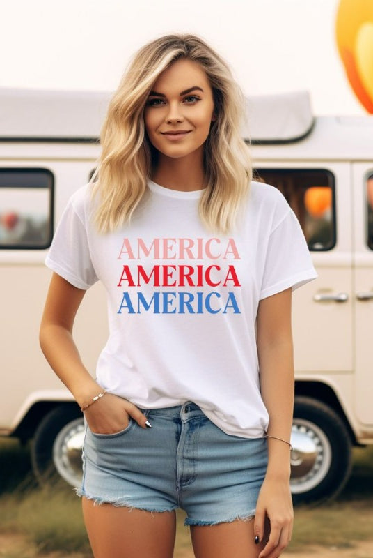 Close-up image of a USA July 4th graphic tee with the word 'America' repeated three times in bold lettering on the front. This festive tee is perfect for celebrating Independence Day in style and showing off your patriotic spirit on a white graphic tee. 