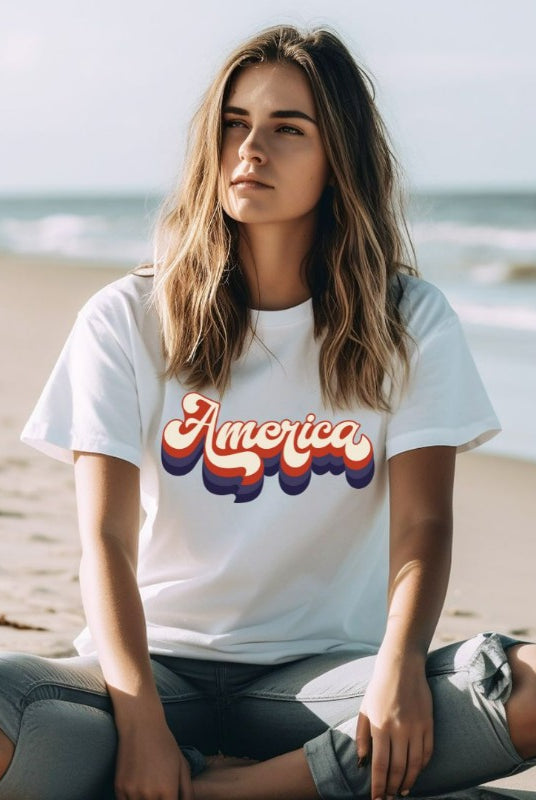 Close-up image of a USA July 4th graphic tee with the word 'America' spelled out in funky retro lettering on the front. This vintage-inspired tee is perfect for adding a fun and nostalgic touch to your Independence Day celebrations on white graphic tee. 