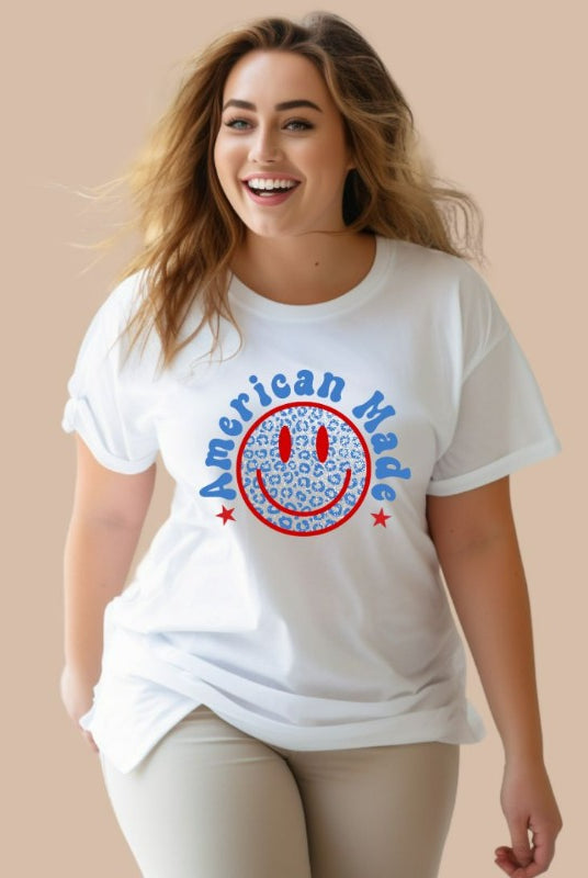 Close-up image of a USA July 4th graphic tee featuring the words 'American Made' surrounded by retro lettering around a bold blue cheetah print retro smiley face on the front. A playful and unique design perfect for celebrating July 4th in style on a white graphic tee.