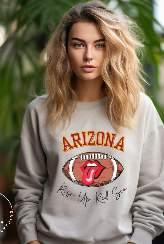 Support the Arizona Cardinals in style with our exclusive sweatshirt featuring the team's name and rallying slogan, "Rise Up Red Sea." On a grey sweatshirt.