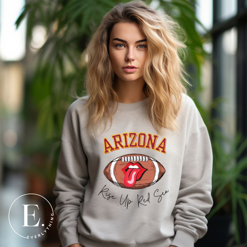 Support the Arizona Cardinals in style with our exclusive sweatshirt featuring the team's name and rallying slogan, "Rise Up Red Sea." On a grey sweatshirt.