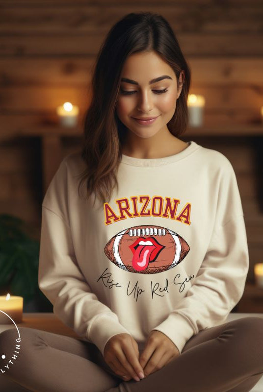 Support the Arizona Cardinals in style with our exclusive sweatshirt featuring the team's name and rallying slogan, "Rise Up Red Sea." On a sand colored sweatshirt. 