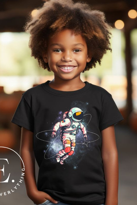 Embark on an intergalactic adventure with our captivating kids' shirt! Featuring a whimsical design of an astronaut floating in space on a black shirt. 