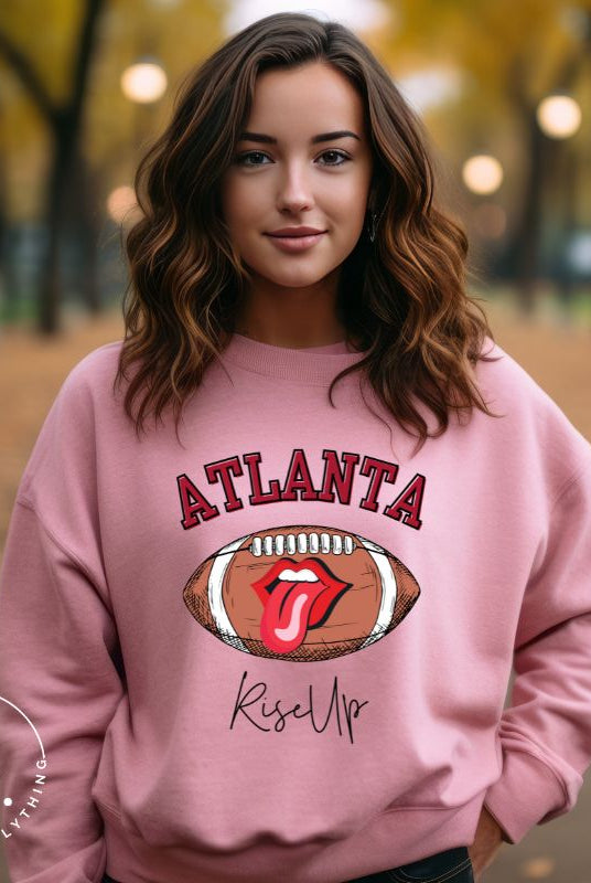 Show your Atlanta Falcons pride with our cozy and warm sweatshirt featuring the team's name and empowering slogan, "Rise Up." On a pink sweatshirt. 
