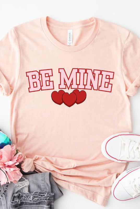 Make your Valentine's Day celebrations even more special with our PNG sublimation digital download! You can create unique and personalized shirts featuring the charming phrase "Be Mine" in a trendy and eye-catching design. Example on Be Mine PNG sublimation on a peach shirt. 