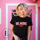 Elevate your Valentine's Day style with our "Be Mine" shirt! Featuring bold athletic lettering and three adorable hearts, on a black shirt. 