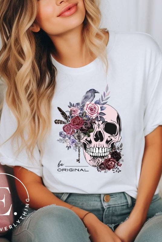 Looking for a unique Halloween shirt? Look no further! Our hauntingly beautiful shirt features a floral skull, raven, and the empowering slogan 'Be Original'. Stand out from the crowd with this unforgettable statement piece on a white shirt. 