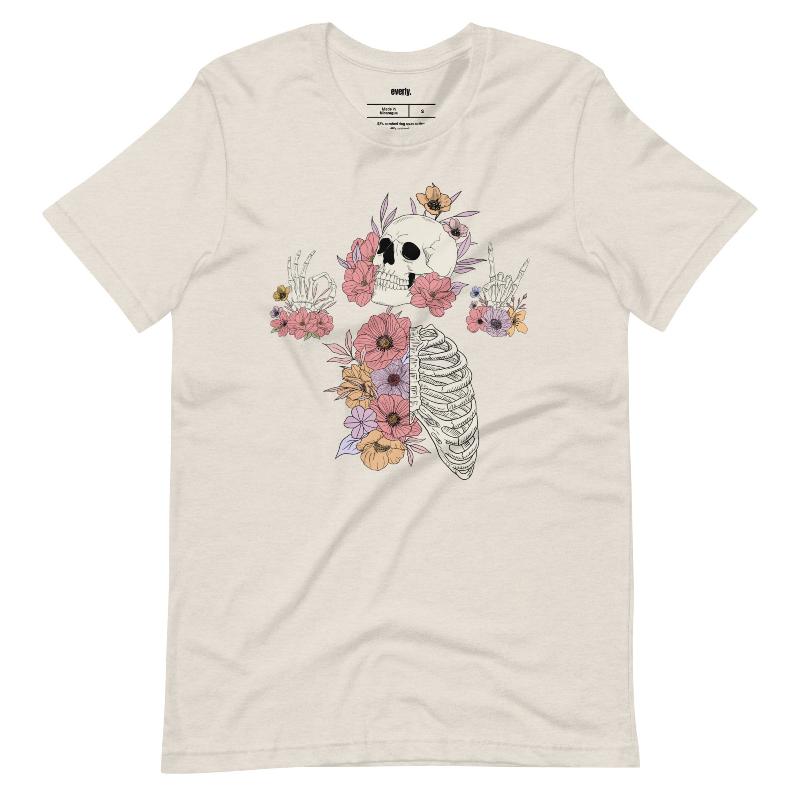 Heather dust t-shirt featuring a detailed skeleton design with ribcage and hands intertwined with soft, colorful flowers, blending gothic and floral aesthetics.