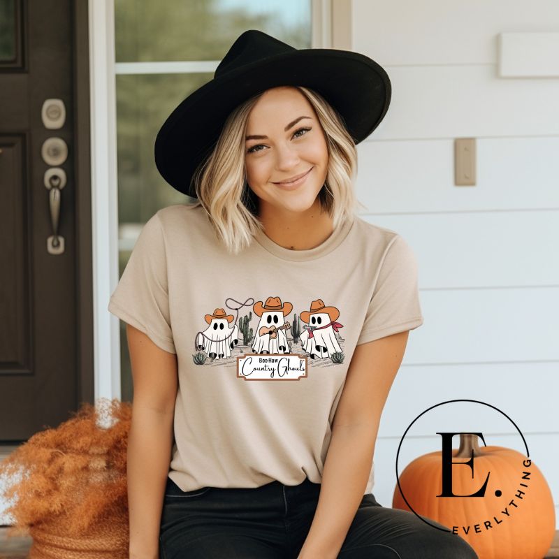 Get ready for a boot-stompin' Halloween with our country-themed PNG sublimation download. Featuring ghostly cowboys in cowboy hats, lassos, and playing country music, all accompanied by the catchy saying 'Boo-Haw Country Ghouls.' PNG example on a tan shirt. 