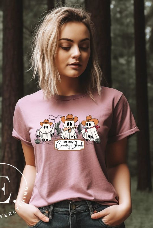 Boo-haw! Get ready for a hauntingly good time with our country ghost shirt. Featuring a spirited spectator donning cowboy hat, this shirt combines Halloween with country charm. The clever play on words, ' Country Ghouls,' adds a fun twist on a pink shirt. 