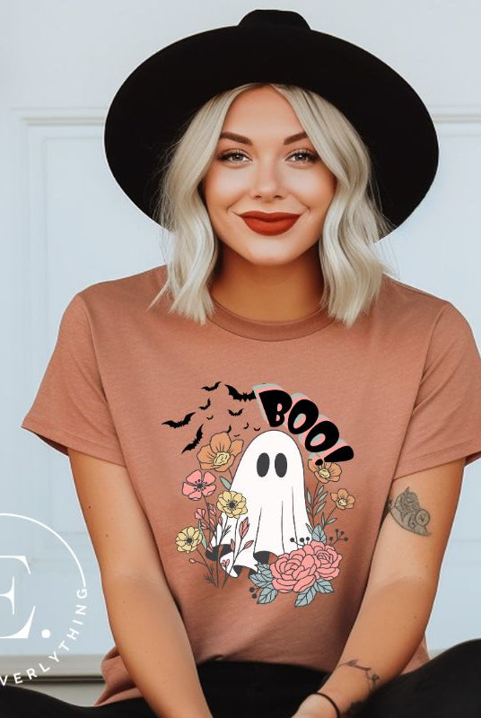 Get ready for Halloween with our cute and spooky ghost-themed shirt! Featuring a whimsical design with a cute ghost, flowers, and bats in a starry sky, it's the perfect blend of spooky and sweet on a mauve shirt. 