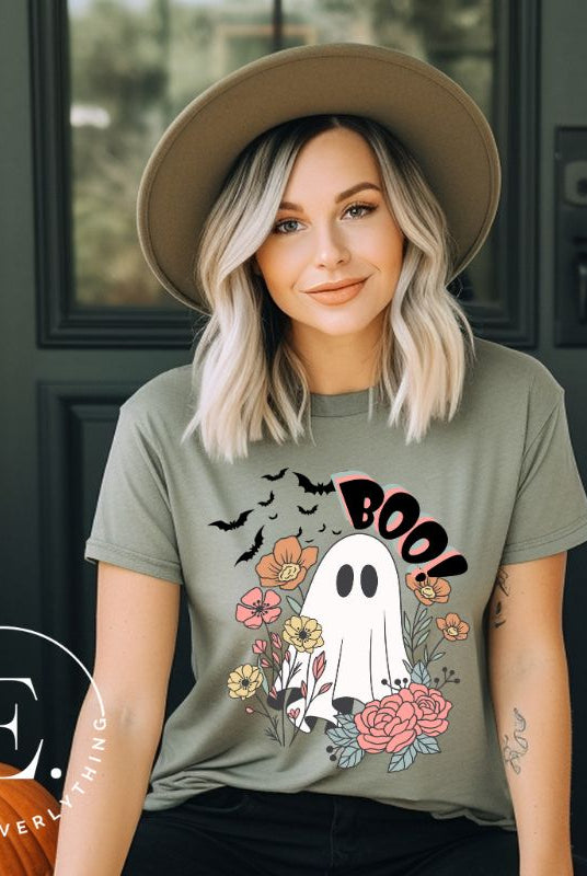 Get ready for Halloween with our cute and spooky ghost-themed shirt! Featuring a whimsical design with a cute ghost, flowers, and bats in a starry sky, it's the perfect blend of spooky and sweet on a green shirt. 