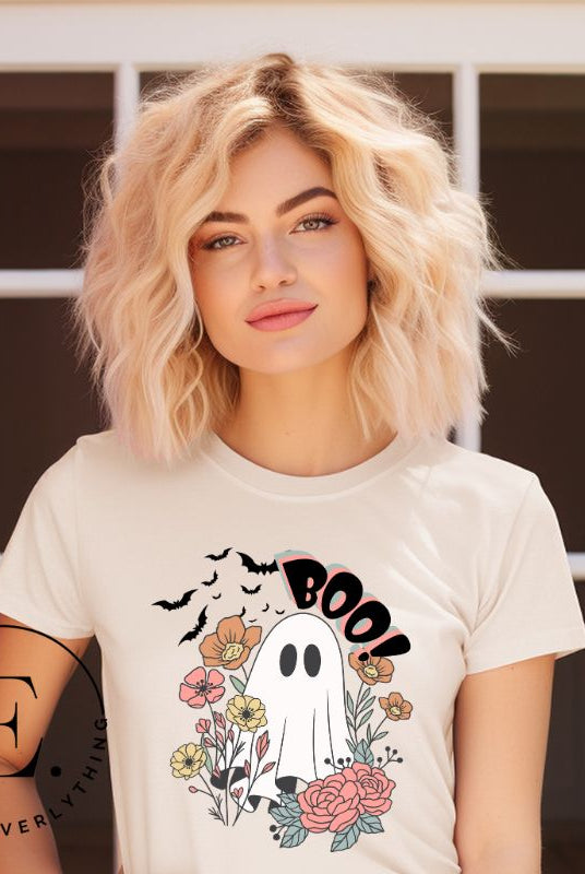Get ready for Halloween with our cute and spooky ghost-themed shirt! Featuring a whimsical design with a cute ghost, flowers, and bats in a starry sky, it's the perfect blend of spooky and sweet on a soft cream shirt. 