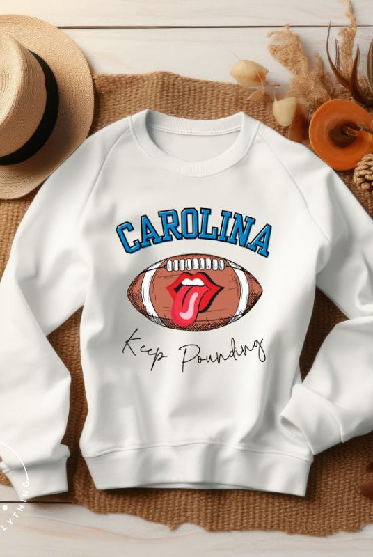 Support the Carolina Panthers in style with our modern and trendy sweatshirt featuring the team's name and powerful teams slogan, "Keep Pounding." On a white sweatshirt. 