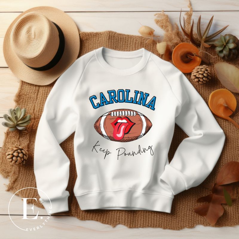 Support the Carolina Panthers in style with our modern and trendy sweatshirt featuring the team's name and powerful teams slogan, "Keep Pounding." On a white sweatshirt. 