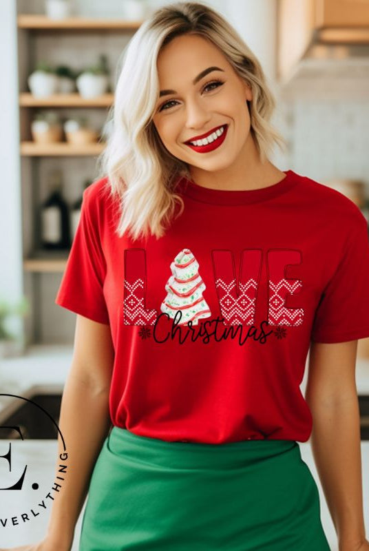 Spread love and joy this holiday season with our Christmas shirt featuring the classic Christmas tree cake, which is incorporated into the word "Love" on a red colored shirt.
