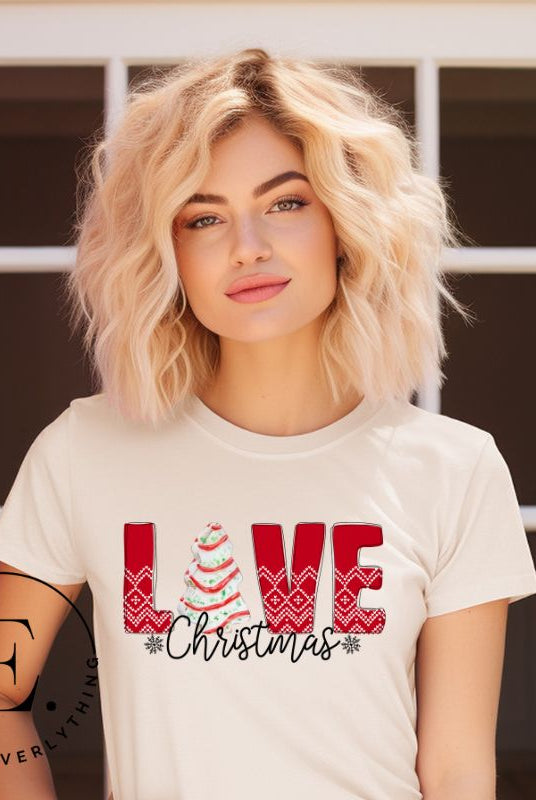 Spread love and joy this holiday season with our Christmas shirt featuring the classic Christmas tree cake, which is incorporated into the word "Love" on a soft cream colored shirt.