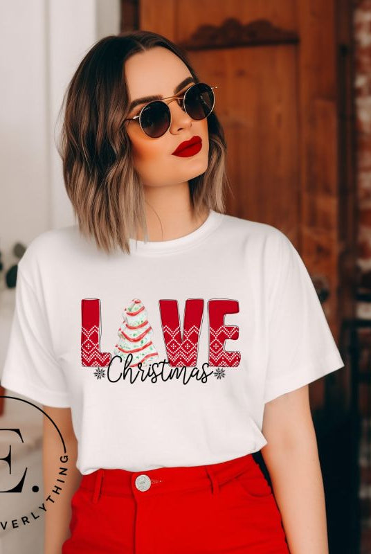 Spread love and joy this holiday season with our Christmas shirt featuring the classic Christmas tree cake, which is incorporated into the word "Love" on a white colored shirt.
