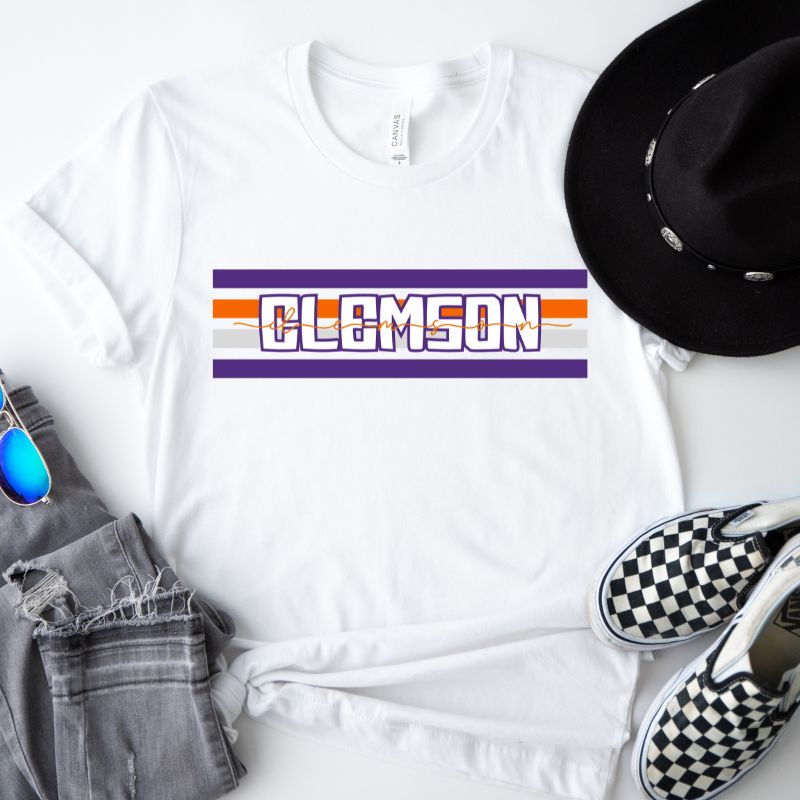 Bella + Canvas 3001 unisex shirt with Clemson University stripe design in purple, orange, and white, with "Clemson" written in bold letters on a white graphic tee.