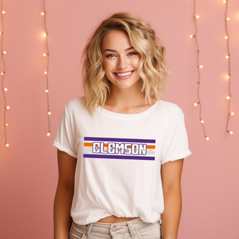 Bella + Canvas 3001 unisex shirt with Clemson University stripe design in purple, orange, and white, with "Clemson" written in bold letters on a white graphic tee.