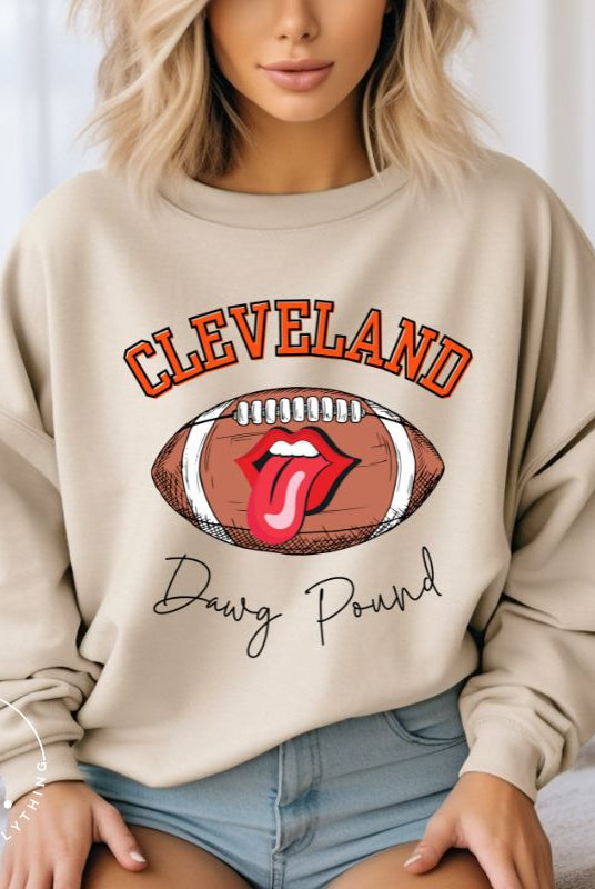 Show your Cleveland Browns pride with our exclusive sweatshirt featuring the team's name and iconic slogan, "Dawg Pound." On a sand colored sweatshirt. 