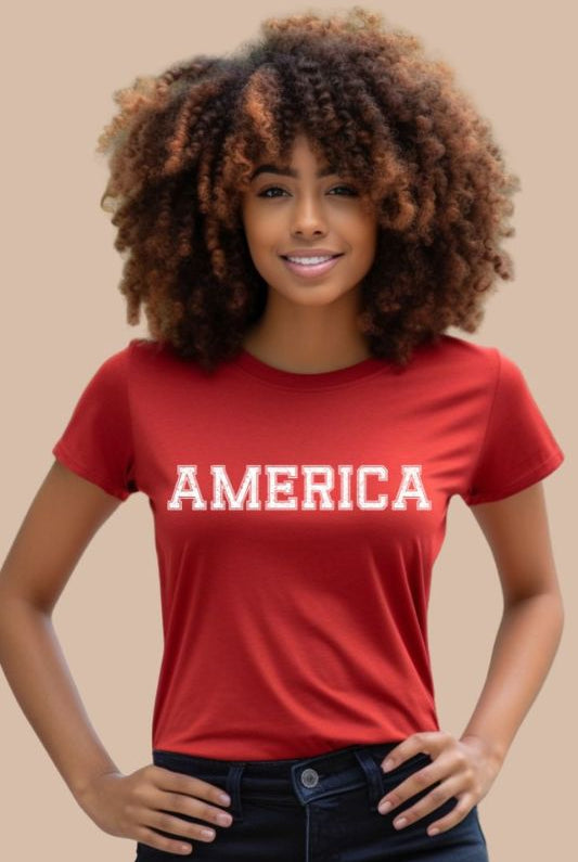 Close-up image of a USA July 4th graphic tee with the word 'America' spelled out in cool sports lettering on the front. This fun and stylish tee is perfect for showing off your patriotic spirit and celebrating the 4th of July in true American style on a red tee. 