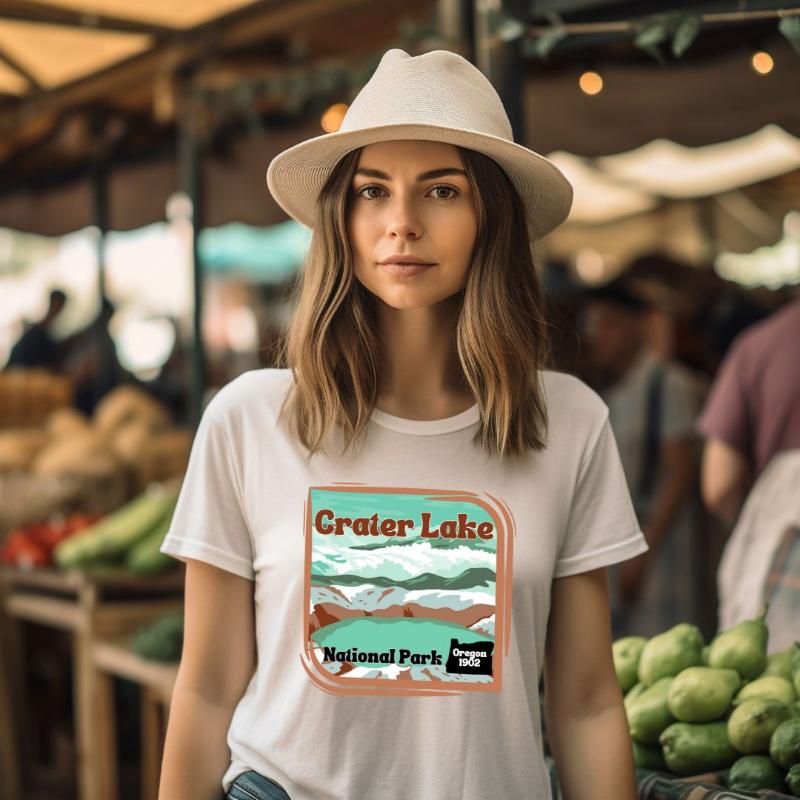 a colorful graphic of Crater Lake National Park, featuring mountains, water, and the text "Crater Lake National Park Oregon 1902 on a white shirt. 