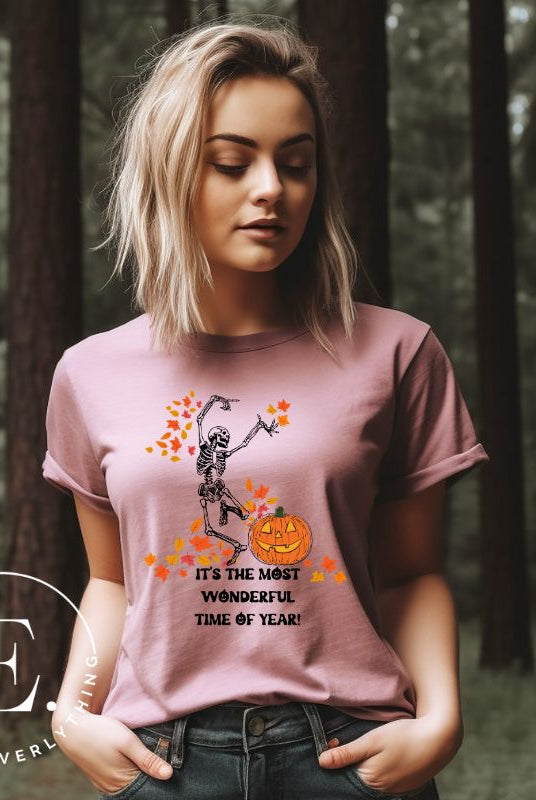 Get into the spirit of fall with our Dancing Skeleton T-shirt. This playful shirt features a whimsical skeleton surrounded by falling leaves, on a pink shirt. 