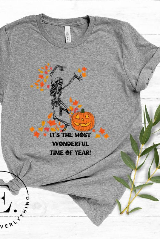 Get into the spirit of fall with our Dancing Skeleton T-shirt. This playful shirt features a whimsical skeleton surrounded by falling leaves, on a grey shirt.