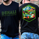 Black Bella + Canvas 3001 t-shirt with front and back Denali National Park designs. The front features "Denali National Park | Alaska - 1917" in neon green text, and the back showcases a colorful, detailed illustration of Denali's landscapes and wildlife.