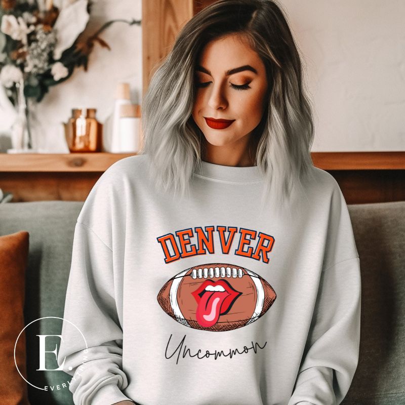 Get ready to show your support for the Denver Broncos in style with our exclusive sweatshirt featuring the team's iconic name and their slogan "uncommon." On a grey sweatshirt. 