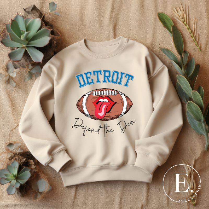 Get ready to show your Detroit Lions pride with this stylish sweatshirt featuring a football and playful lips and tongue design. Complete with the team's slogan "Defend the Den" and the iconic Detroit wordmark, this cozy  sand colored sweatshirt. 