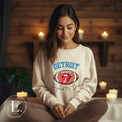 Get ready to show your Detroit Lions pride with this stylish sweatshirt featuring a football and playful lips and tongue design. Complete with the team's slogan "Defend the Den" and the iconic Detroit wordmark, this cozy sand colored sweatshirt. 