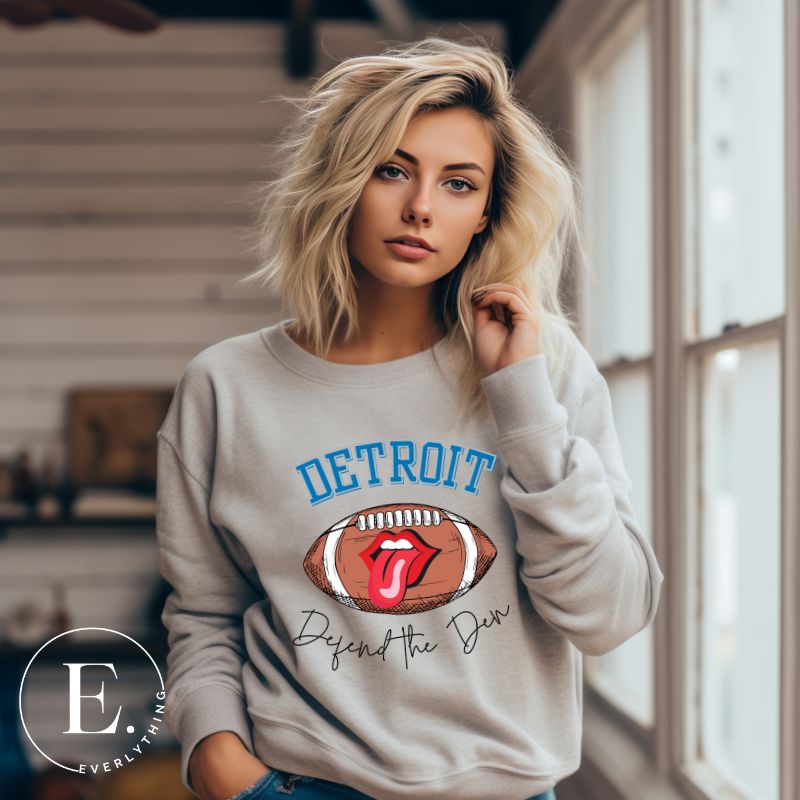 Get ready to show your Detroit Lions pride with this stylish sweatshirt featuring a football and playful lips and tongue design. Complete with the team's slogan "Defend the Den" and the iconic Detroit wordmark, this cozy  grey sweatshirt.