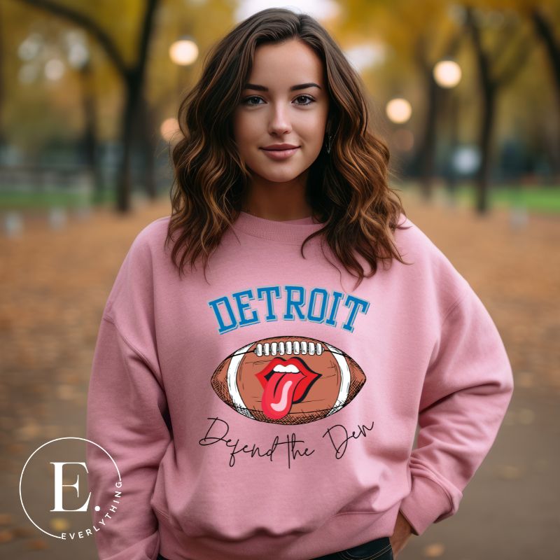 Get ready to show your Detroit Lions pride with this stylish sweatshirt featuring a football and playful lips and tongue design. Complete with the team's slogan "Defend the Den" and the iconic Detroit wordmark, this cozy  pink sweatshirt. 