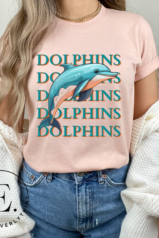 Introducing the Bella Canvas 3001 unisex graphic t-shirt that will make a splash! Dive into style with our Dolphins Dolphins Dolphins Dolphins tee, featuring a playful illustration of a dolphin for the Miami Dolphins football team on a heather prism peach shirt. 