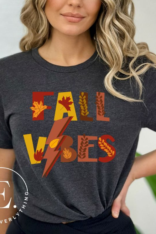 Get into the autumn spirit with our Fall Vibes shirt. Featuring the words 'Fall Vibes' with a creative twist- a lighting bolt replacing the 'I'- this shirt captures the energy of the season. Adorned with leaves, it adds a touch of nature's beauty on a dark grey shirt. 