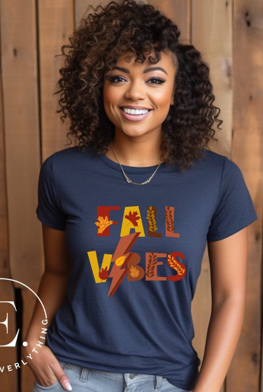 Get into the autumn spirit with our Fall Vibes shirt. Featuring the words 'Fall Vibes' with a creative twist- a lighting bolt replacing the 'I'- this shirt captures the energy of the season. Adorned with leaves, it adds a touch of nature's beauty on a navy shirt.