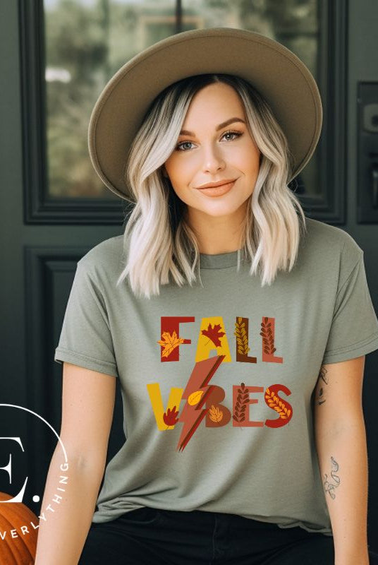 Get into the autumn spirit with our Fall Vibes shirt. Featuring the words 'Fall Vibes' with a creative twist- a lighting bolt replacing the 'I'- this shirt captures the energy of the season. Adorned with leaves, it adds a touch of nature's beauty on a green shirt. 