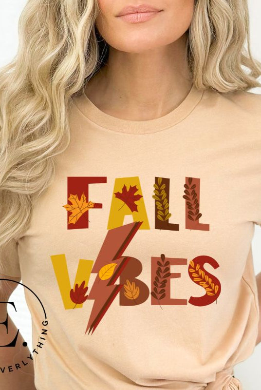 Get into the autumn spirit with our Fall Vibes shirt. Featuring the words 'Fall Vibes' with a creative twist- a lighting bolt replacing the 'I'- this shirt captures the energy of the season. Adorned with leaves, it adds a touch of nature's beauty on a tan shirt. 