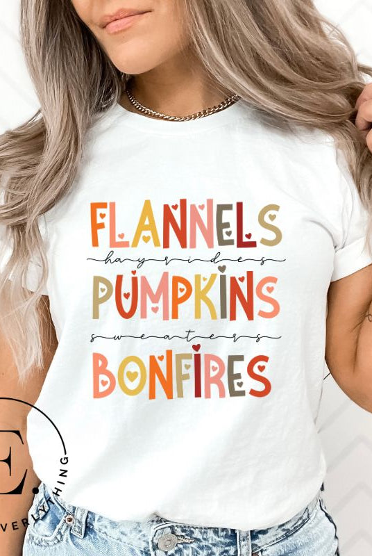 Embrace the cozy spirit of fall with our Flannel, Hayrides, Pumpkins, Sweaters, Bonfires shirt. Featuring the iconic fall elements, this shirt celebrates the season of warmth and comfort on a white shirt. 