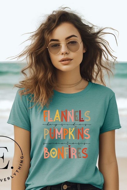 Embrace the cozy spirit of fall with our Flannel, Hayrides, Pumpkins, Sweaters, Bonfires shirt. Featuring the iconic fall elements, this shirt celebrates the season of warmth and comfort on a teal shirt. 