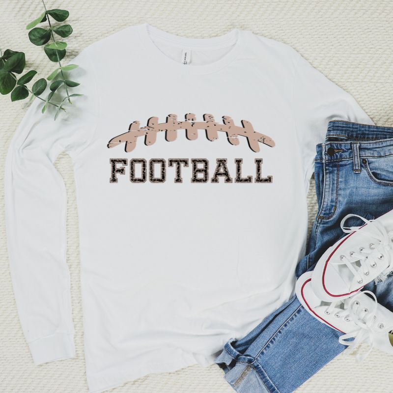 A white long-sleeve shirt featuring a football graphic with cheetah print details and the word "FOOTBALL" in bold, playful lettering. The design is placed prominently on the chest, perfect for sports enthusiasts.