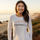 A white long-sleeve shirt featuring a football graphic with cheetah print details and the word "FOOTBALL" in bold, playful lettering. The design is placed prominently on the chest, perfect for sports enthusiasts.