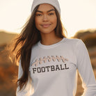 A white long-sleeve shirt featuring a football graphic with cheetah print details and the word "FOOTBALL" in bold, playful lettering. The design is placed prominently on the chest, perfect for sports enthusiasts.