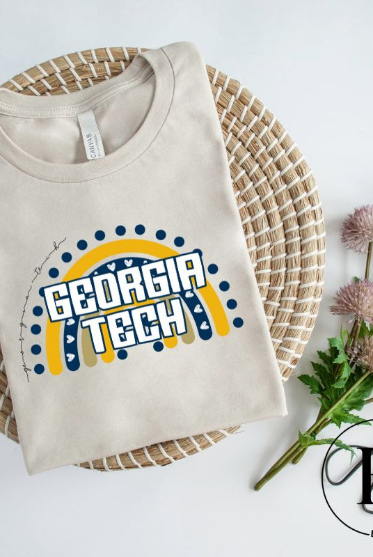 Elevate your Georgia Tech pride with this boho-inspired university t-shirt. The Georgia Tech colors shine through on a vibrant rainbow background, showcasing the school's name in a trendy and unique way on a cream shirt. 