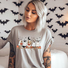 Grey t-shirt featuring a row of dogs dressed in ghost costumes with pumpkins, perfect for Halloween fun and dog lovers.